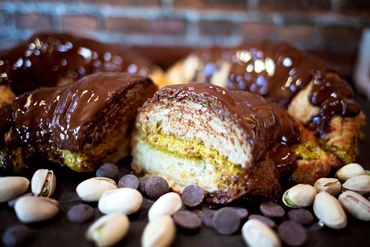 Chocolate-covered pistachio pastry with scattered pistachios and chocolate chips.