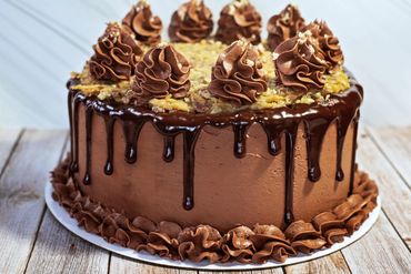 Rich chocolate cake with chocolate ganache drips and decorative frosting swirls.