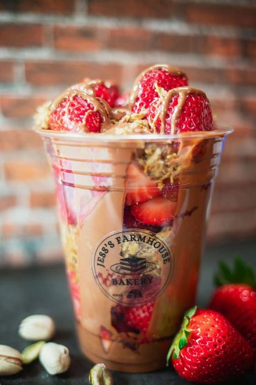 Strawberry parfait with granola and chocolate drizzle in a clear Jess's Farmhouse Bakery cup.