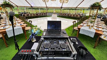 DJ setup overlooking a decorated wedding reception area with tables and a dance floor.