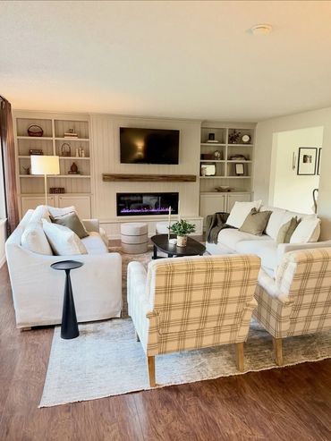 Cozy living room with neutral tones, plaid armchairs, and a custom build modern fireplace wall with