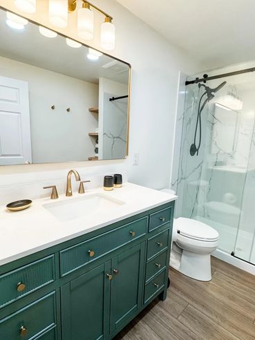 Modern bathroom new build with green vanity, white countertop, and glass shower enclosure in Port Or