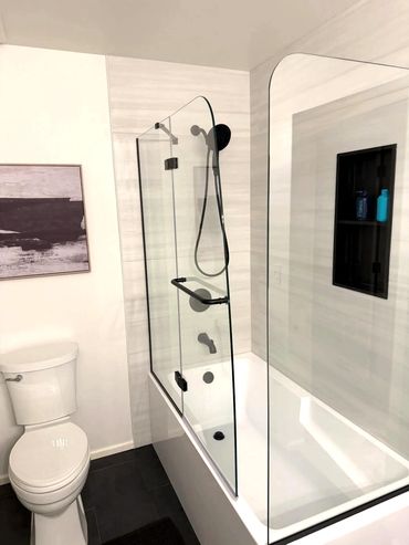 Modern bathroom with large format tile, soaking tub, glass shower enclosure and black fixtures in Si