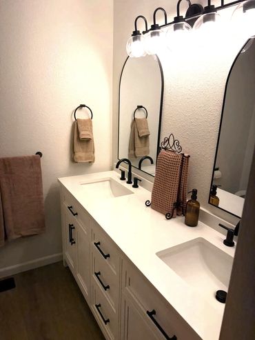 Modern bathroom with dual mirrors and sinks, black fixtures, and beige towels in Port Orchard, Washi