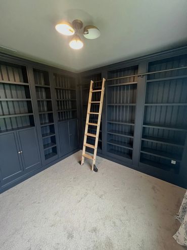 Floor to ceiling blue bookshelves and a wooden ladder in Silverdale, Washington.