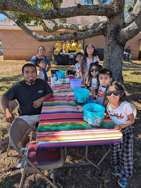 Family gathered around a colorful picnic table outdoors on a sunny day.