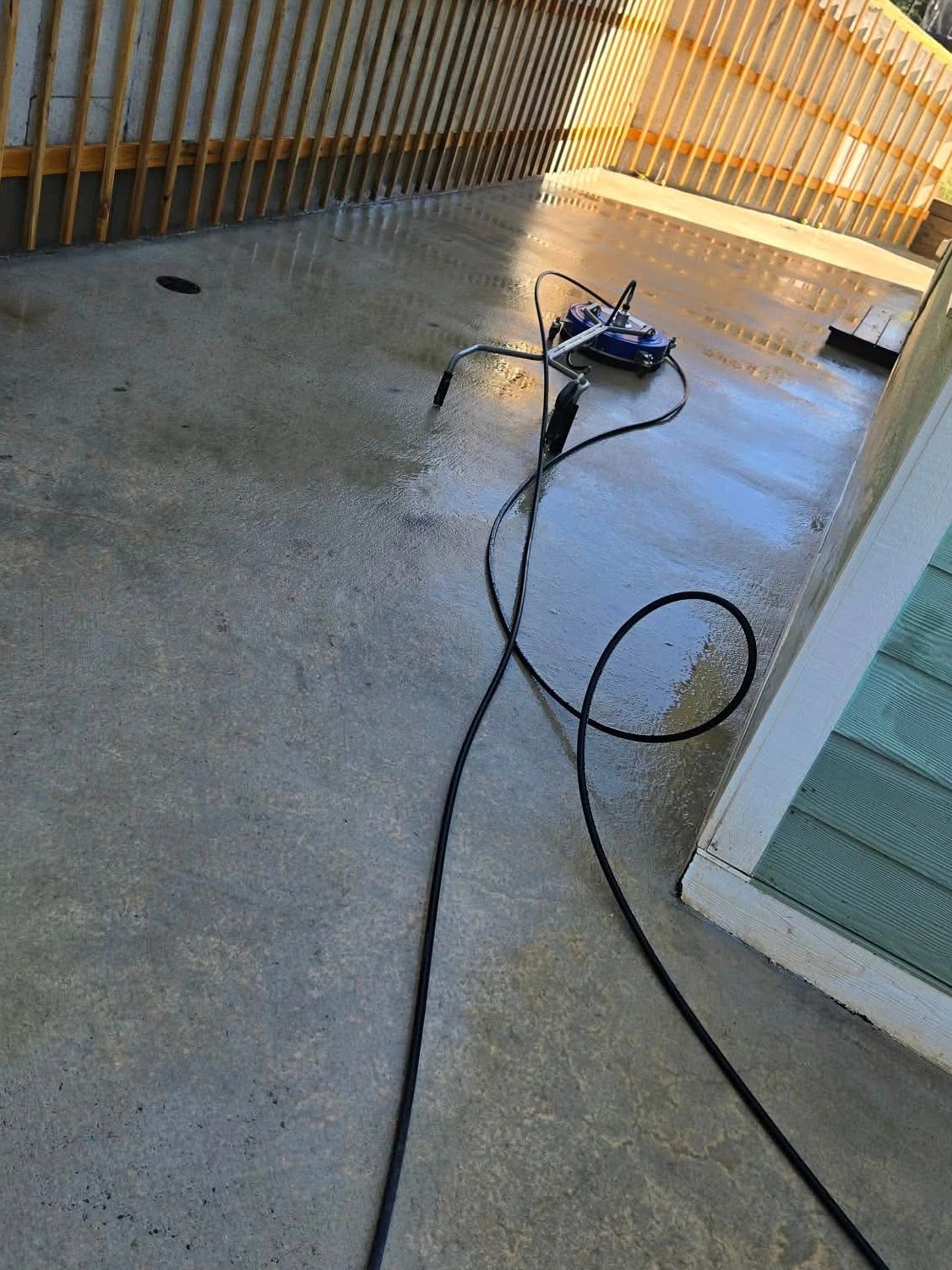 Surface cleaner attached to a hose cleaning a concrete patio.