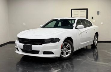 White Dodge Charger sedan parked indoors with black grille and alloy wheels.