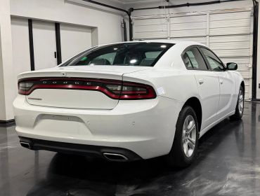White Dodge Charger parked inside a garage with closed door.