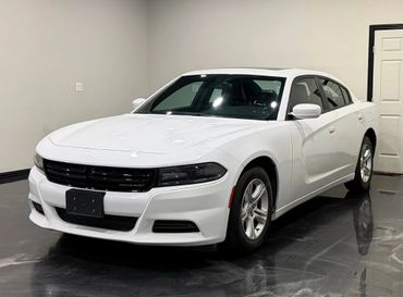 White Dodge Charger parked indoors with black grille and sleek design.