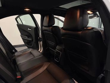 Interior view of a car's backseat with black leather seats and open door.