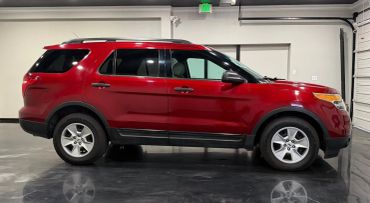 Red SUV parked indoors on shiny floor under bright lights.