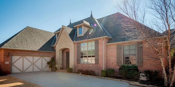 Bright sunny day shows a modern brick house with a large driveway and garage.