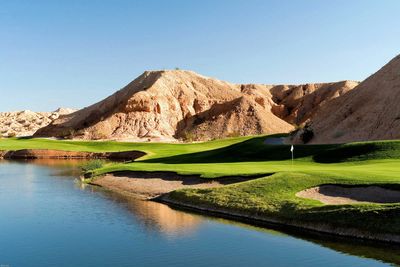 Golf course near desert hills with water body.