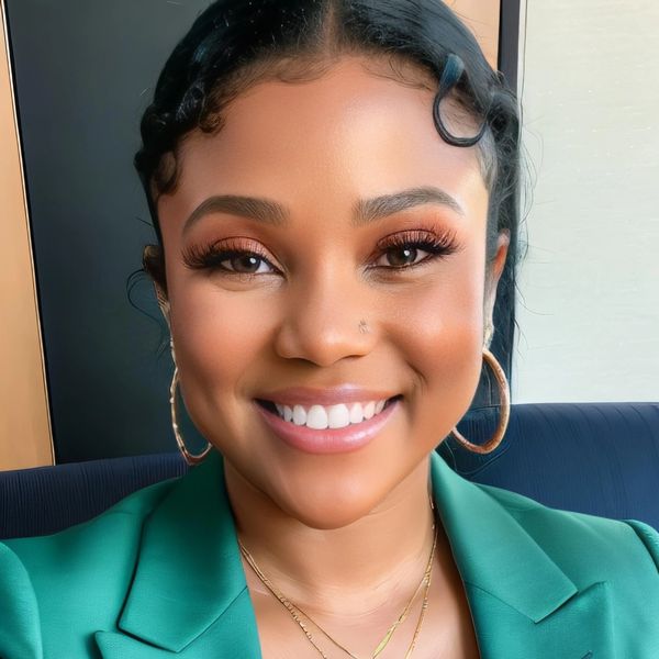 A smiling woman with braided hair and gold hoop earrings.