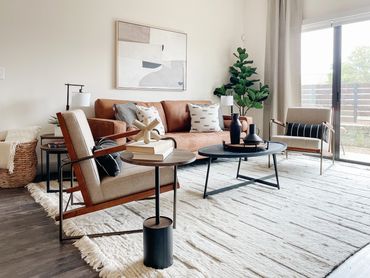 Model apartment living room with camel sofa, modern chairs, and abstract art at Axis 3700 in Texas