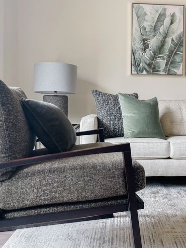 Model apartment living room with neutral seating with green pillows and art at Axis 3700 in Texas