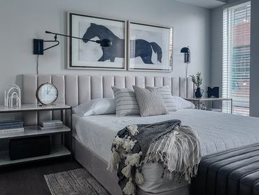 Model unit design with horse diptych, upholstered headboard, chic neutral bedding and modern sconces
