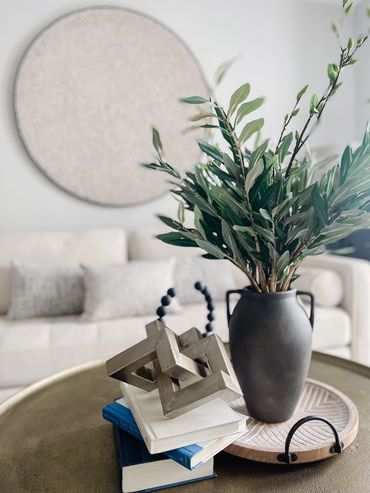 Living room with neutral new sofa behind decorative greenery at model unit of multifamily property