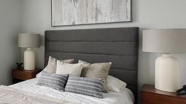 Bedroom with neutral soft art juxtaposed with dark gray bed in model unit of multifamily property