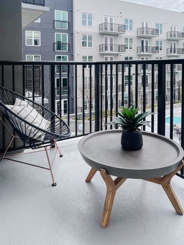 Multifamily model unit outdoor balcony with modern furnishings over pool at High Street in Atlanta
