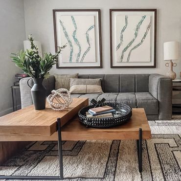 Model apartment with modern art, dark gray sofa, layered tables, and a geometric rug at High street