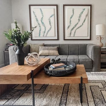 Multifamily interior model with modern gray sofa, abstract art, curated decor, and geometric rug