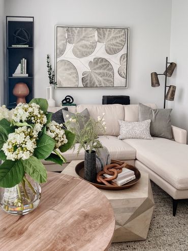 Living room with neutral textured fabrics layered with green pops in model of multifamily property