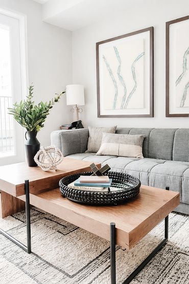 Model apartment with modern art, dark gray sofa, layered tables, and a geometric rug at High street
