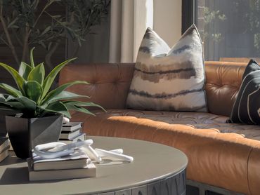 Detail of tufted cognac leather sofa with shibori throw pillows and round coffee table in Windsor St