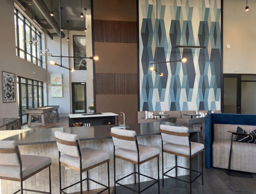 Windsor Stadium Walk clubhouse seating area with white swivel chairs, cognac leather sofa, and wood