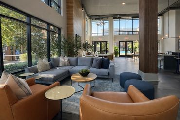 Renovated Windsor Stadium Walk clubhouse main lounge with sectional, cognac swivel chairs, round ott