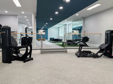 renovated multifamily fitness center with mirrored walls, modern equipment, and turf training zone