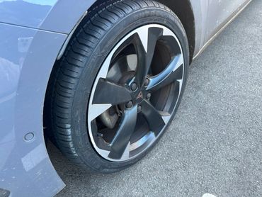 Close-up of a car tire and alloy wheel on asphalt.