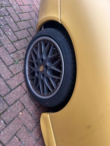 Close-up of a Porsche car wheel on a brick driveway.