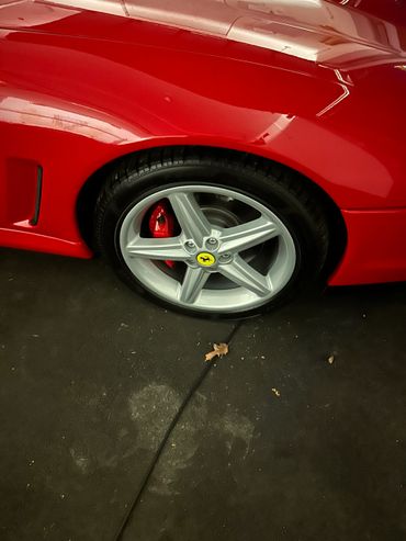 Close-up of a red Ferrari wheel with a silver rim and yellow prancing horse logo.