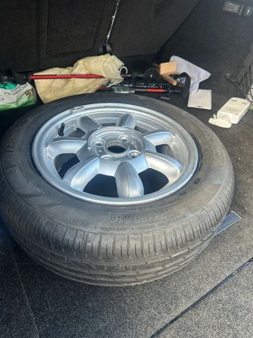 Spare tire with a silver rim in a car trunk.
