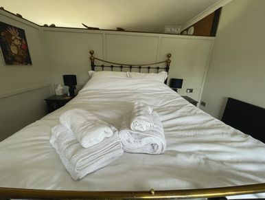Bedroom with a made bed and folded towels.