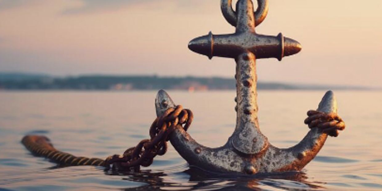 Rusty anchor partially submerged in calm water during sunset.
