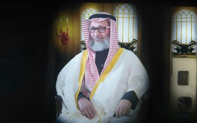 Man in traditional Middle Eastern attire with glasses and a white beard.