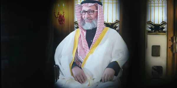 Elderly man in traditional Middle Eastern attire seated indoors.