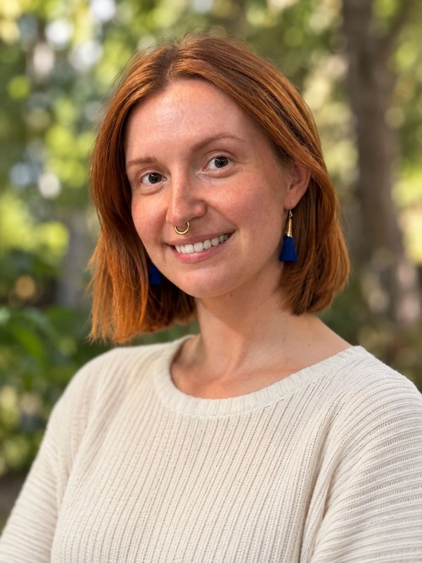 Smiling woman with red hair and blue tassel earrings.