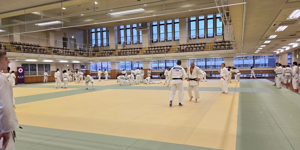 Martial arts training session in a spacious dojo with many participants.
