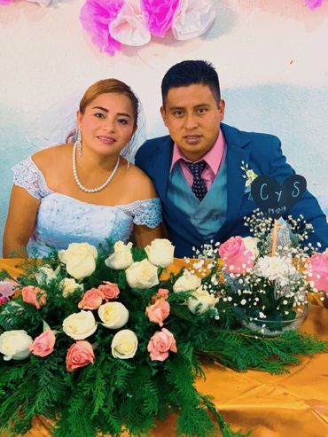 Bride and groom sitting together at a flower-adorned wedding table.