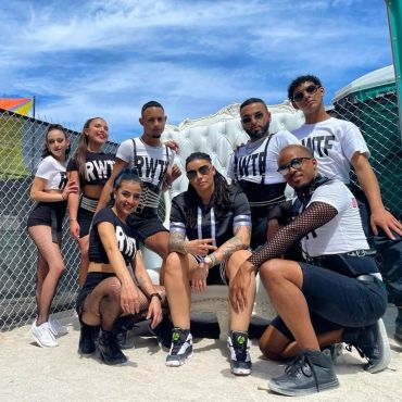 Group of dancers posing outdoors with stylish outfits and sunglasses.