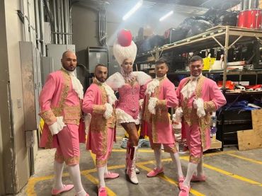 Group in elaborate pink and white costumes backstage.