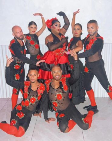 Group dressed in black and red floral costumes posing.