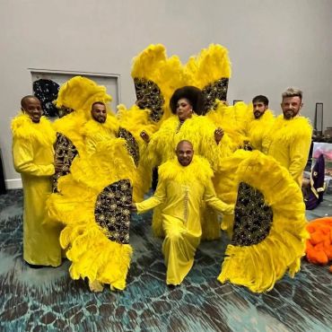 Group in vibrant yellow feathered costumes posing indoors.