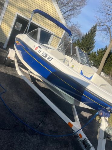 a boat on a trailer in a driveway that just had the hull polished
