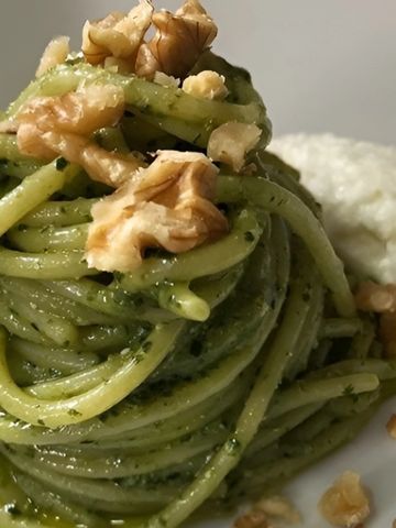 Plato de espaguetis con pesto genovés, crema de burrata y nueces.